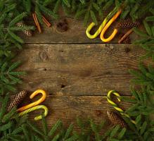 Christmas tree branch with cones, cinnamon, dittany and candy cane on wooden background with copyspace photo