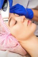 Young woman receiving facial ultrasonic cleaning photo