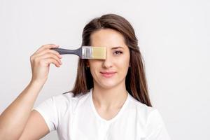 Woman hiding her eye with paintbrush photo