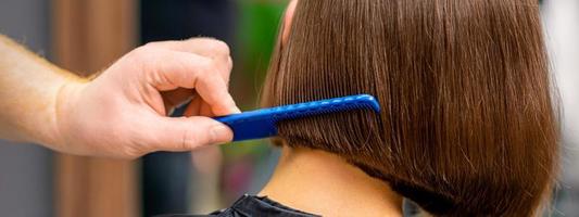 Hairdresser combing hair of woman photo