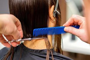 Hairdresser cuts hair of woman photo