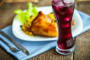 Dishes from chicken thigh with rice and lettuce and a glass of juice with ice photo