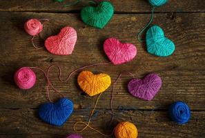 Multicolored Hearts with a balls of thread on old shabby wooden background photo