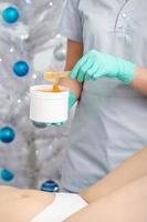 Cosmetologist holds jar with sugaring paste photo