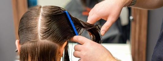 Hairdresser combing hair of woman photo