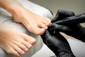 Pedicurist removes cuticle from toes photo