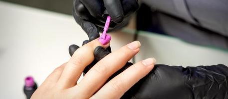 Manicure master applying pink nail polish photo