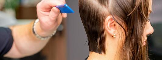 peluquero haciendo Corte de pelo de joven mujer foto