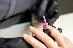 Manicure master applying pink nail polish photo