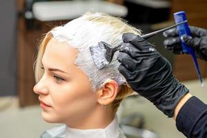 Hairdresser applying white dye to hair photo