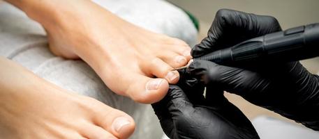 Pedicurist removes cuticle from toes photo