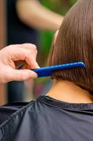 Hairdresser combing hair of woman photo