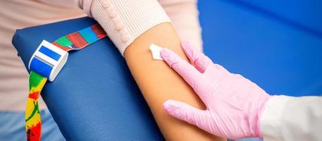 Nurse applying cotton swab to arm photo