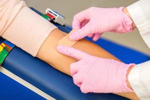 Nurse applying adhesive plaster on arm photo