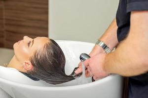 Hairdresser rinses hair of woman photo