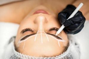 Beautician marking eyebrows with pencil photo