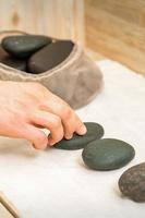 Masseur takes black massage stones photo