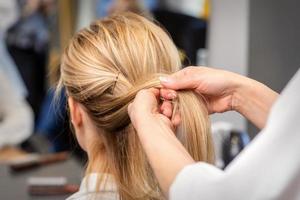 Hairdresser's hands braiding client's hair photo