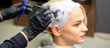 Hairdresser applying white dye to hair photo