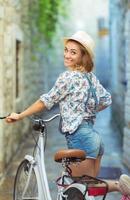 Happy woman with bicycle on street of old town photo