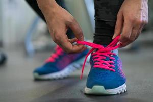 Running shoes - woman tying shoe laces. Woman getting ready for engage in the gym photo