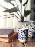 Chineese mug and teapot over wooden tabler with old books photo