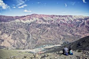 Two peaple watching stunning colorful mountains. El Hornacal. Jujuy, Argentina.