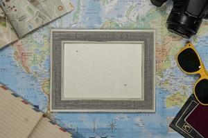 Travel Flat lay of an empty frame, sunglasses, passport, camera, over a world map photo