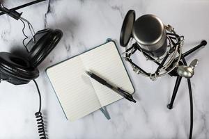 Flat lay of a podcast setting with microphone, headphones and a notebook photo