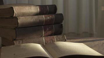 abierto antiguo libro y pila de antiguo libros en un de madera mesa en amanecer ligero foto