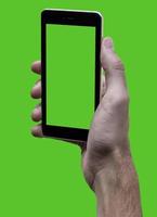 Male hand holding black cellphone with green croma screen at isolated Green background. photo