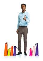 Happy african american man with shopping bags and holding credit card on white background. Shopping photo