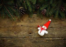 Christmas tree branches with snowman on wooden texture photo