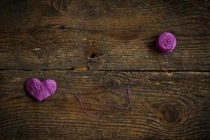 Purple Heart with a ball of thread on on old shabby wooden background photo