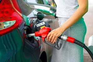 mujer llena gasolina dentro el coche a un gas estación foto