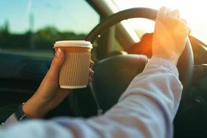 Woman with coffee to go driving her car photo