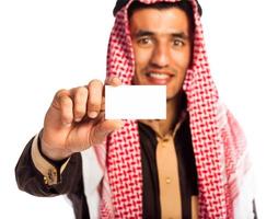 joven sonriente árabe demostración negocio tarjeta en mano aislado en blanco