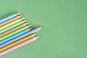 Pastel colored pencils, top view on green background, illustration concept, education and back to school photo