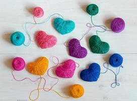 Multicolored Hearts with a balls of thread on white wooden background photo