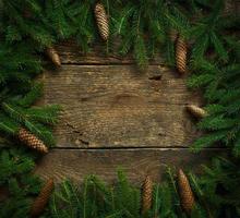 Christmas tree branches with cones on wooden texture ready for your design photo