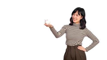 Portrait of young Asian woman casual uniform holding white piggy bank isolated on white background, Financial and bank saving money concept photo