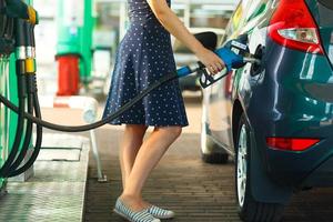 mujer llena gasolina dentro el coche a un gas estación foto