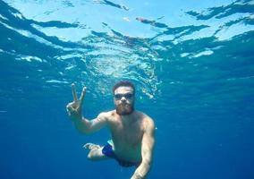 hombre haciendo submarino selfie Disparo con selfie palo en azul mar foto