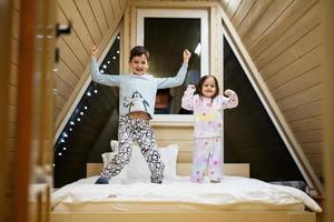 niños en suave calentar pijama jugando a de madera cabina hogar. concepto de infancia, ocio actividad, felicidad. hermano y hermana teniendo divertido y jugando juntos. foto