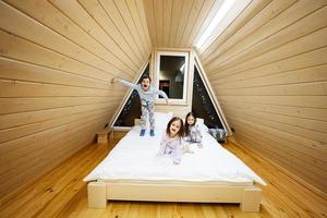 niños en suave calentar pijama jugando a de madera cabina hogar. concepto de infancia, ocio actividad, felicidad. hermano y hermanas teniendo divertido y jugando juntos. foto