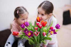 Two sisters with spring tulip bouquet.  Holiday decor with flowers colorful tulips. photo