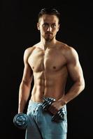 Athletic man with dumbbells on the black background photo