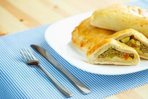 sabroso pastel relleno con carne en un blanco plato y azul a cuadros manteles foto