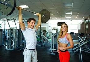 atlético Pareja con barra con pesas haciendo ejercicios en el gimnasio foto