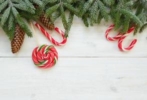 Christmas border with fir tree branches with cones and candy cane on white wooden boards ready photo